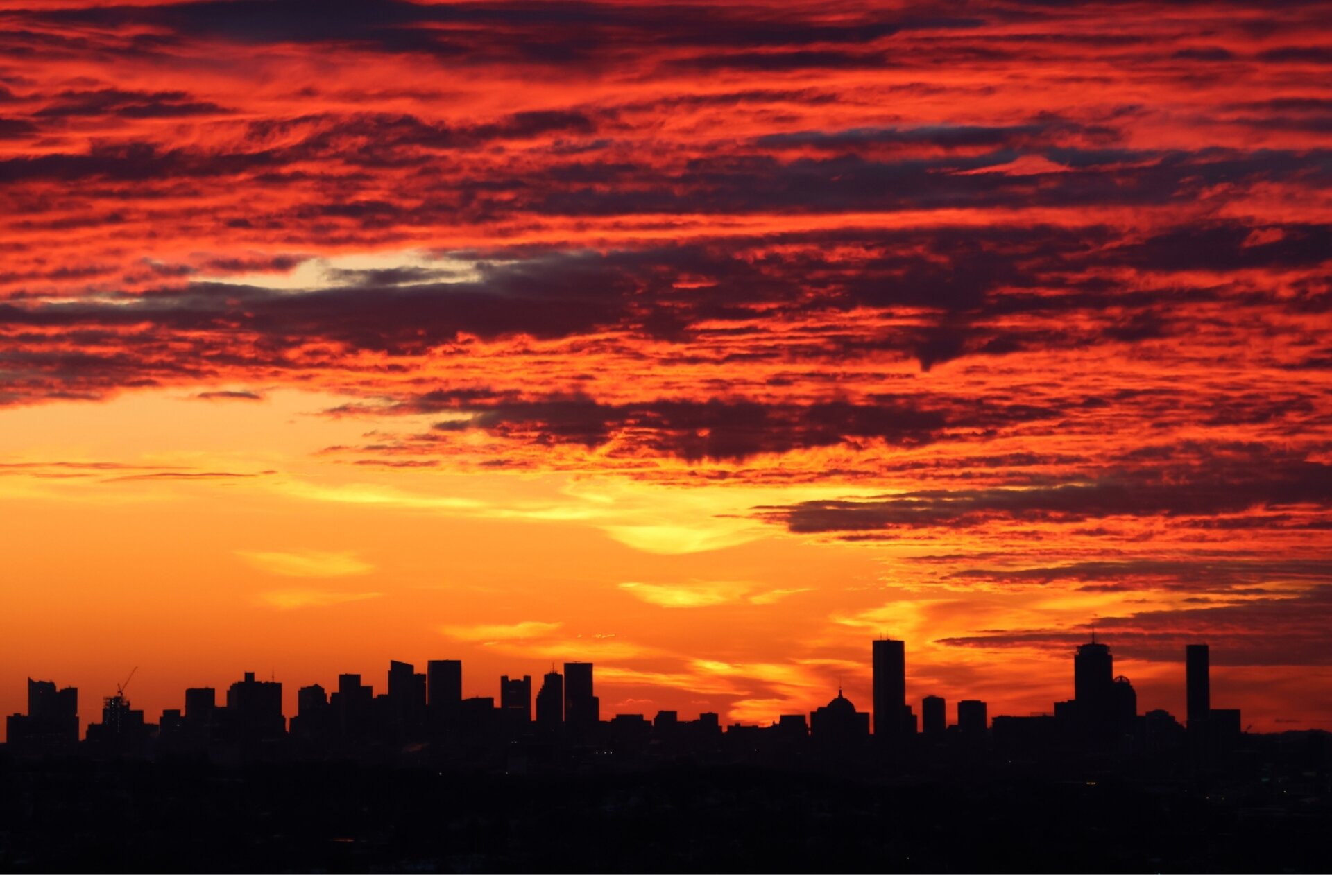 Boston skyline at sunrise — dramatic red and amber sky over the city silhouette